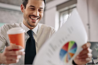 Uśmiechnięty pan w jednej ręce trzymający kubek z kawą a w drugiej wykres przedstawiający ścieżkę kariery w finansach.