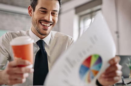 Uśmiechnięty pan w jednej ręce trzymający kubek z kawą a w drugiej wykres przedstawiający ścieżkę kariery w finansach.