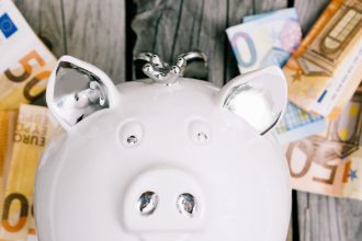 Biała skarbonka i banknoty euro jako symbol oszczędzania na fundusze akcyjne.