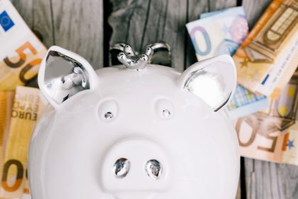 Biała skarbonka i banknoty euro jako symbol oszczędzania na fundusze akcyjne.