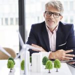 Doświadczony inwestor prezentujący makietę farmy wiatrowej jako alternatywne inwestycje w sektorze zielonej energii.