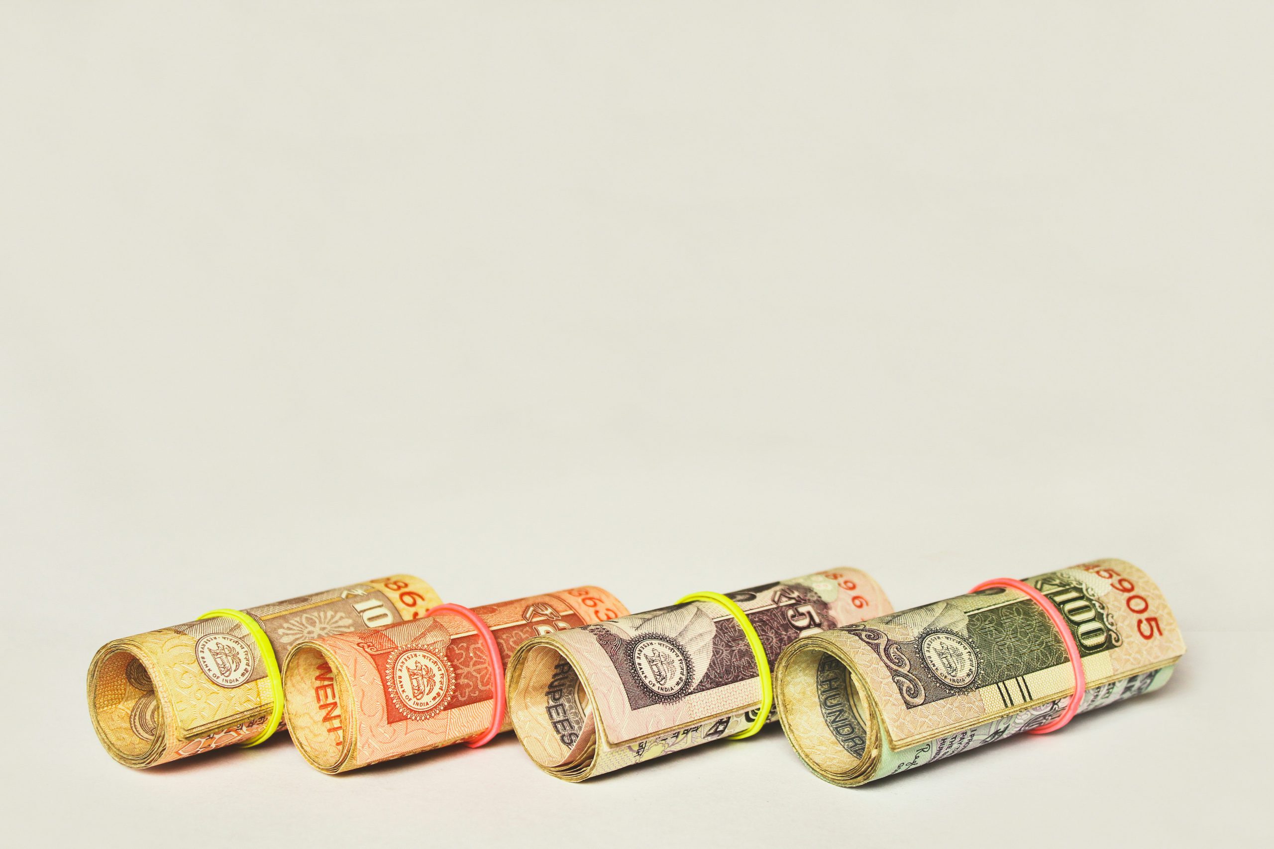 Zwinięte banknoty rupii indyjskich spięte kolorowymi gumkami symbolizujące oszczędności i zarządzanie pieniędzmi.